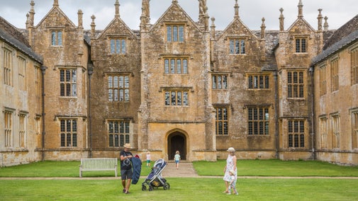 A family explore the grounds immediately in front of the house at Barrington Court, Somerset in summer